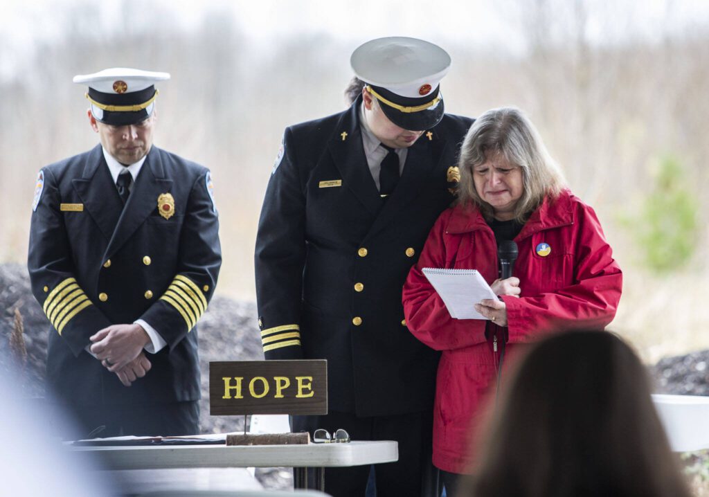 Gail Thompson is comforted by Chaplin Joel Johnson while she reads a speech she wrote earlier in the morning at the Oso Memorial on Tuesday, March 22, 2022 in Oso, Washington. (Olivia Vanni / The Herald)
