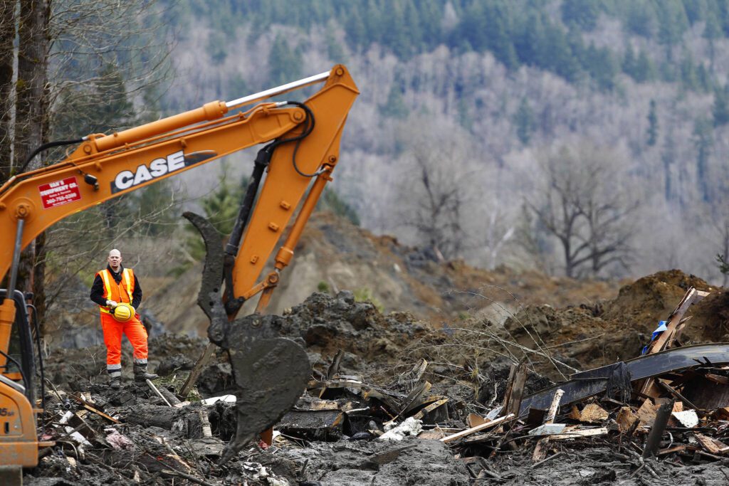 Heavy equipment moves debris on the western edge of the mudslide where near where the slide covered Highway 530 east of Oso, Washington on March 26, 2014. (Mark Mulligan / The Herald)
