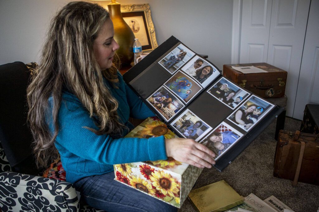 Julie Petersen flips through a family photo album with images of her sister Christina Jefferds and Jefferds’ grand daughter Sanoah Violet Huestis at her home on March 20, 2024 in Arlington, Washington. (Annie Barker / The Herald)
