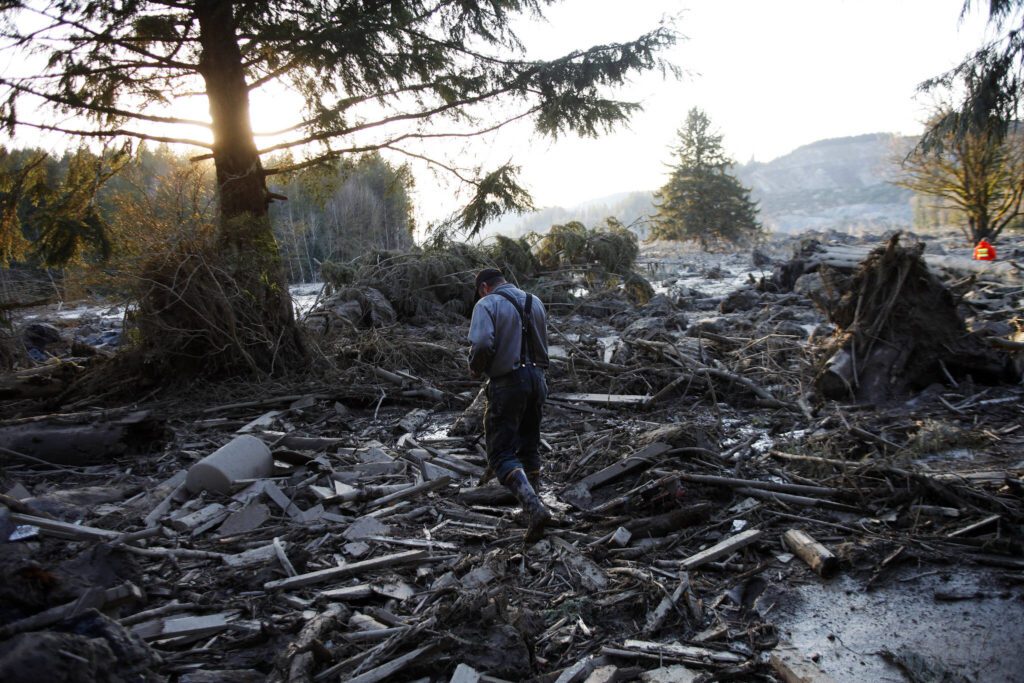 Steve Skaglund walks across rubble left by the slide near Oso, Washington, on March 23, 2014. (Genna Martin/The Herald)
