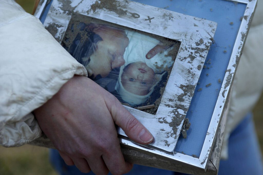 A woman holds family photos pulled from the rubble of the mudslide near Oso, Washington, on March 23, 2014. Many possessions taken during later recovery efforts were collected, decontaminated and stored in an Arlington warehouse until families could identify them. (Genna Martin / The Herald)

