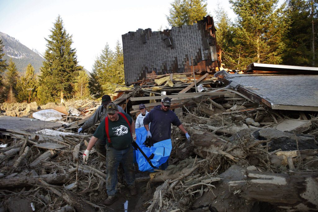 Jason Anderson, Steve Skaglund, Rhonda Cook and Frank Cook recover a body from the east side of the slide on Sunday, March 2014. (Genna Martin / The Herald)
