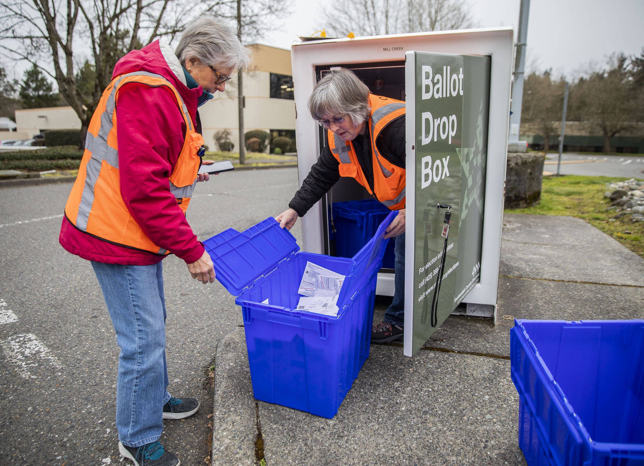 Snohomish County election staff Carolyn Thostenson, left, and Chris Faith, right, collect ballots from a drop box next to the Mill Creek Post Office on Friday, March 8, 2024 in Mill Creek, Washington. (Olivia Vanni / The Herald)