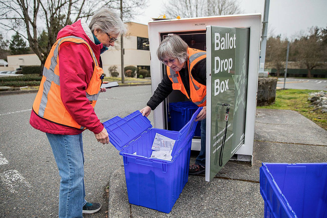 Snohomish County election staff Carolyn Thostenson, left, and Chris Faith, right, collect ballots from a drop box next to the Mill Creek Post Office on Friday, March 8, 2024 in Mill Creek, Washington. (Olivia Vanni / The Herald)