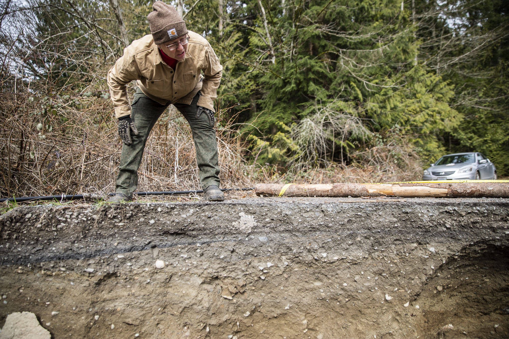 Ellyn Ritchotte looks over the sharp ledge of the washed out road on Wednesday, March 6, 2024 in Marysville, Washington. (Olivia Vanni / The Herald)