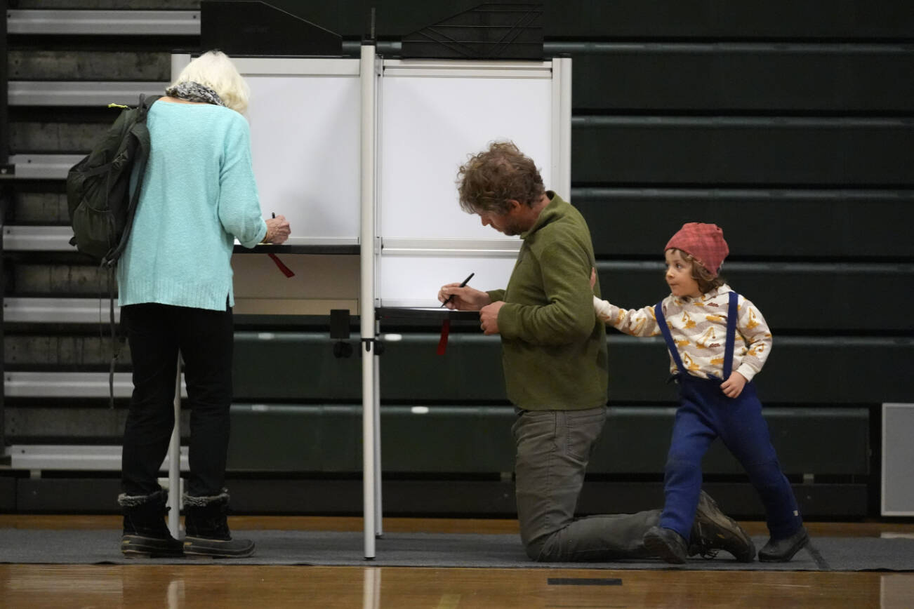 Oliver Paradee accompanies his father, Andrew Paradee, as he fills out his ballot in the primary election, Tuesday, March 5, 2024, in Stowe, Vt.  Super Tuesday elections are being held in 16 states and one territory. Hundreds of delegates are at stake, the biggest haul for either party on a single day.  (AP Photo/Robert F. Bukaty)
