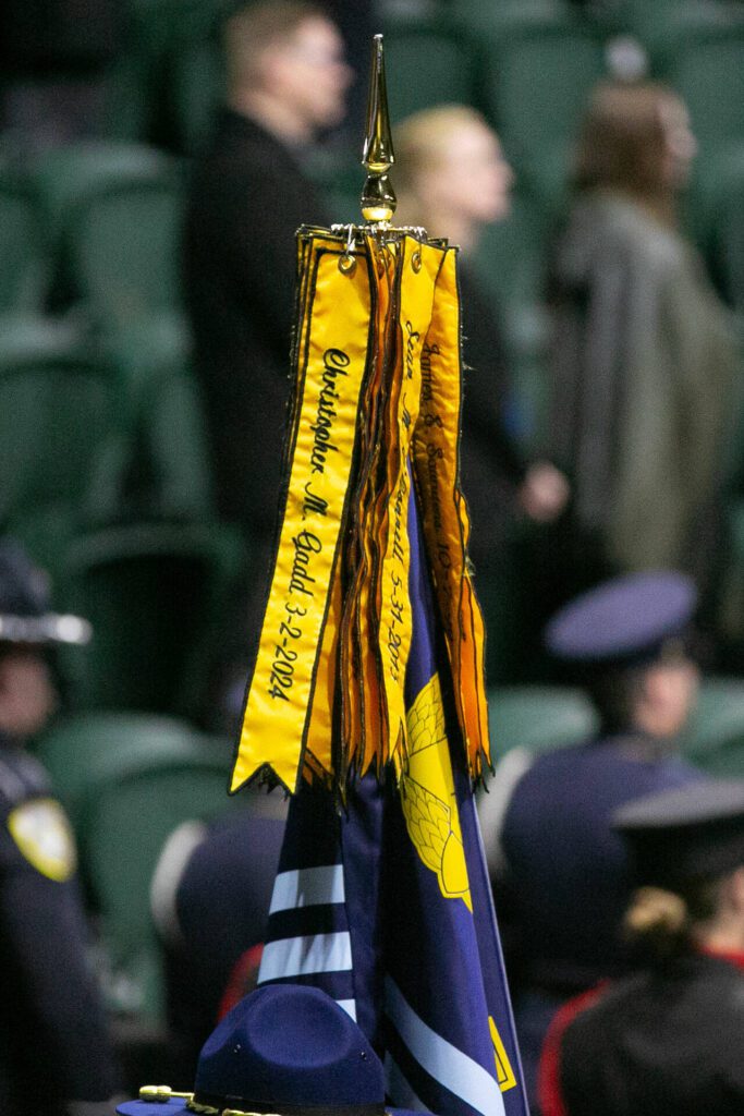 The Washington State Patrol flag bears the name of trooper Chris Gadd at the end of a ceremony on Tuesday, March 12, 2024, at Angel of the Winds Arena in Everett, Washington. (Ryan Berry / The Herald) 
