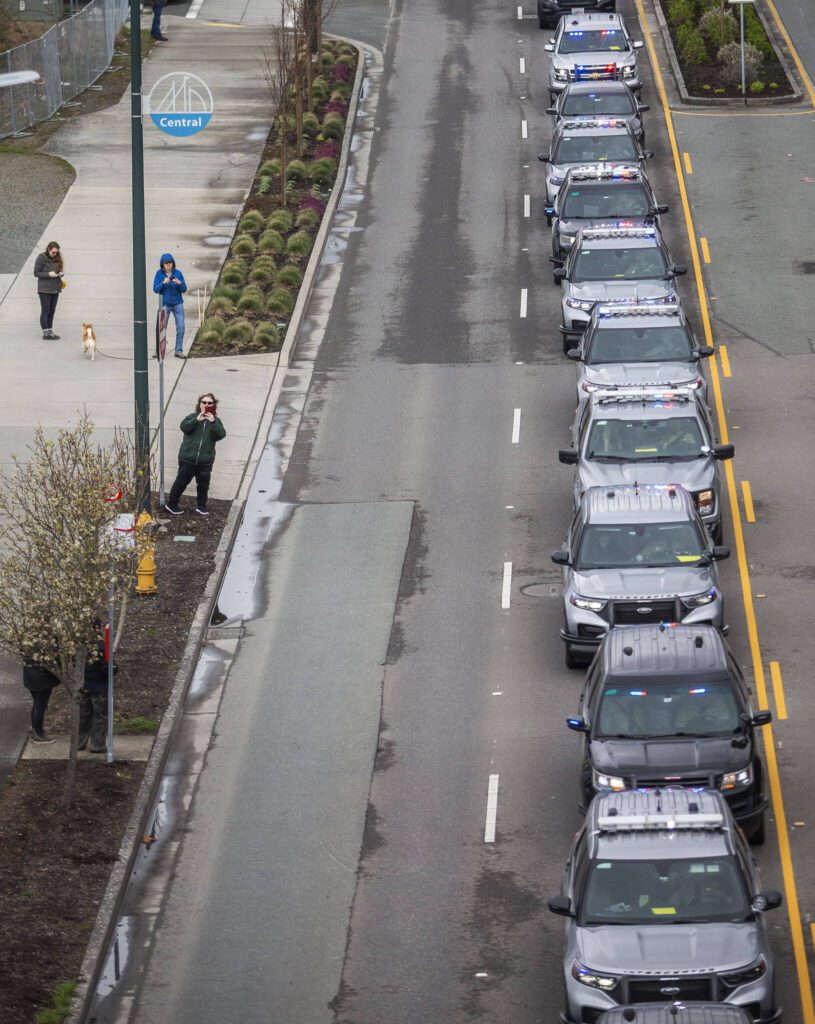 Police cars stop along Marine View Drive during a memorial procession for Washington State Patrol trooper Christopher Gadd on Tuesday, March 12, 2024 in Everett, Washington. (Olivia Vanni / The Herald)
