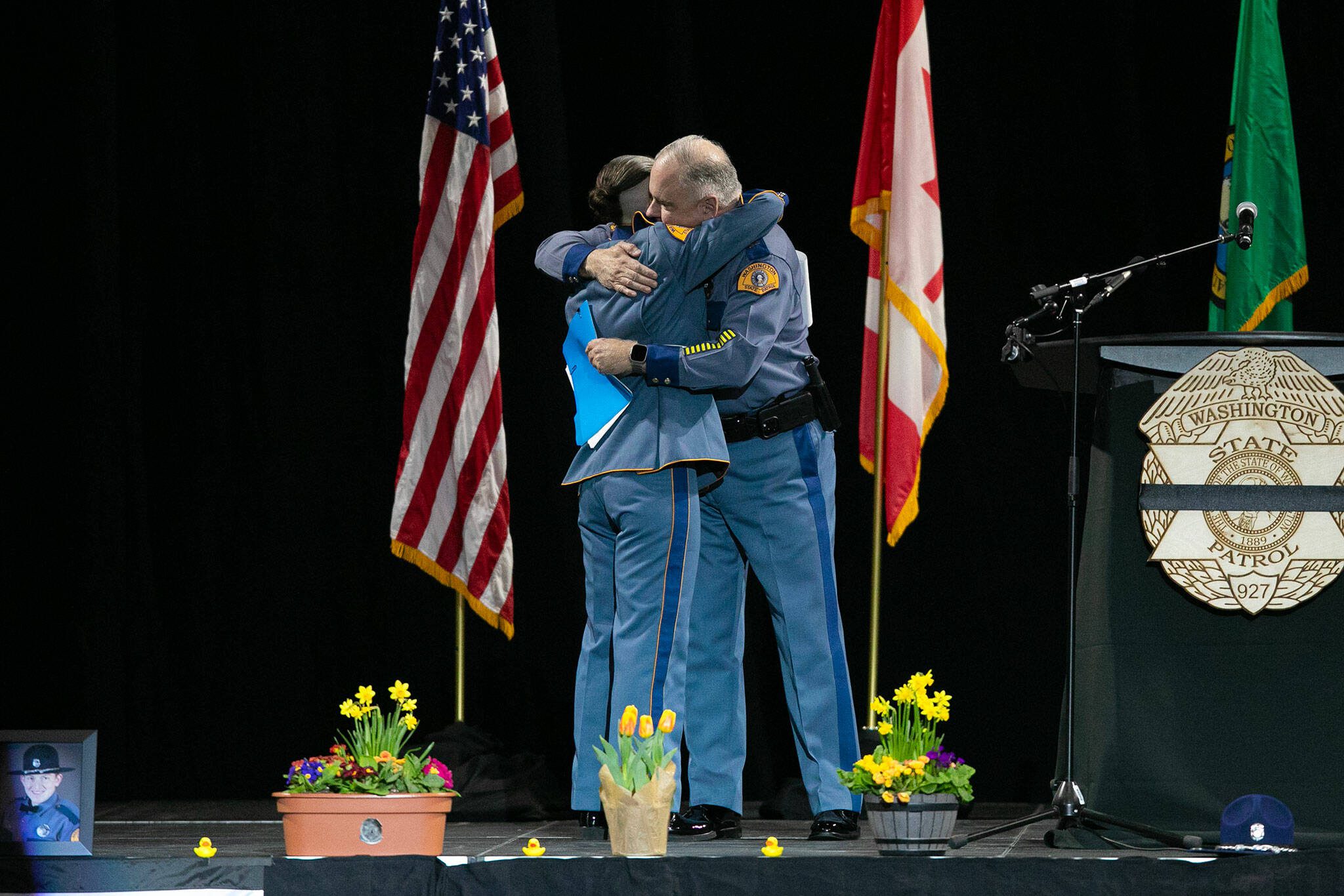 Washington State Patrol Capt. Ron Mead and Cpl. Alexis Robinson embrace during a memorial for Washington State Patrol trooper Chris Gadd on Tuesday, March 12, 2024, at Angel of the Winds Arena in Everett, Washington. (Ryan Berry / The Herald)