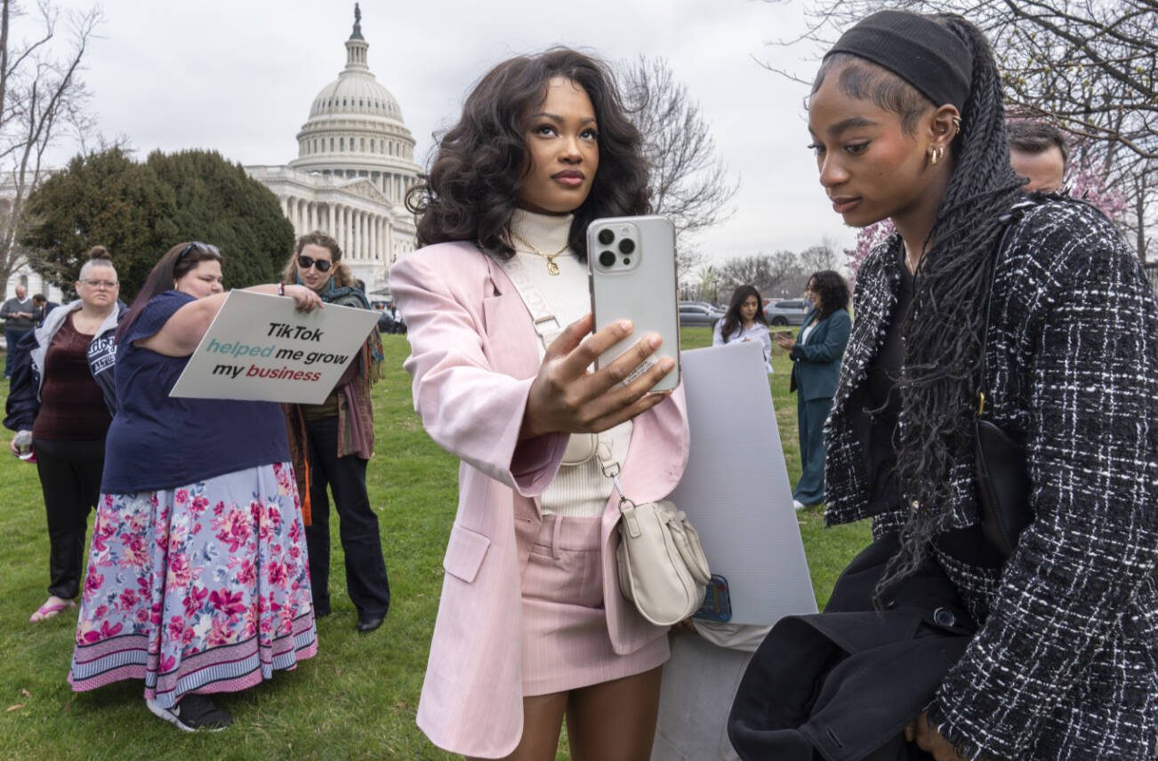 Devotees of TikTok, Mona Swain, center, and her sister, Rachel Swain, right, both of Atlanta, monitor voting at the Capitol in Washington, as the House passed a bill that would lead to a nationwide ban of the popular video app if its China-based owner doesn't sell, Wednesday, March 13, 2024. Lawmakers contend the app's owner, ByteDance, is beholden to the Chinese government, which could demand access to the data of TikTok's consumers in the U.S. (AP Photo/J. Scott Applewhite)