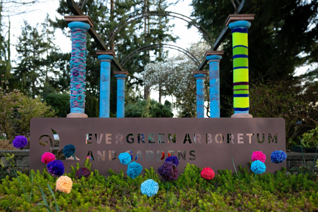 Yarn decorations greet people at the front gate of Evergreen Arboretum and Gardens as part of the Color Storm event on Thursday, March 14, 2024, in Everett, Washington. (Ryan Berry / The Herald)

