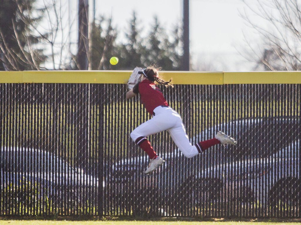 Snohomish’s Avery Clark leaps to try and catch a ball as it goes over the outfield fence during the game Glacier Peak on Friday, March 15, 2024 in Snohomish, Washington. (Olivia Vanni / The Herald)
