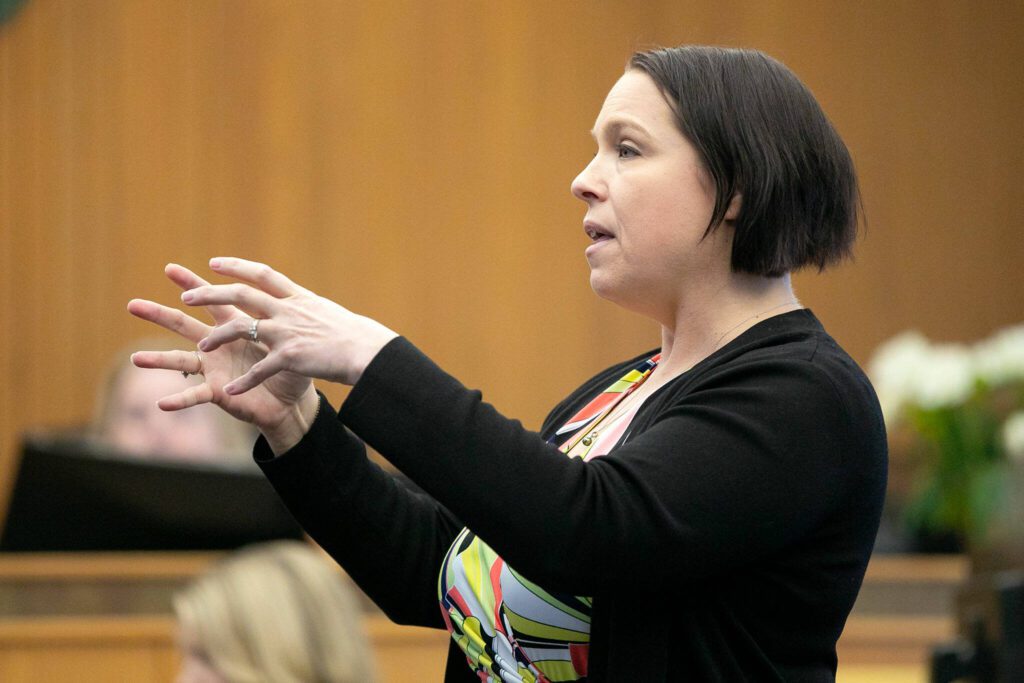 Public defender Heather Wolfenbarger makes a strangling motion while speaking to the jury during opening statements in the trial of Alan Dean, who is accused of the 1993 murder of Melissa Lee, on Monday, March 18, 2024, at Snohomish County Superior Court in Everett, Washington. The defense claims Lee’s ex-boyfriend is the responsible party for her death, not Dean. (Ryan Berry / The Herald)
