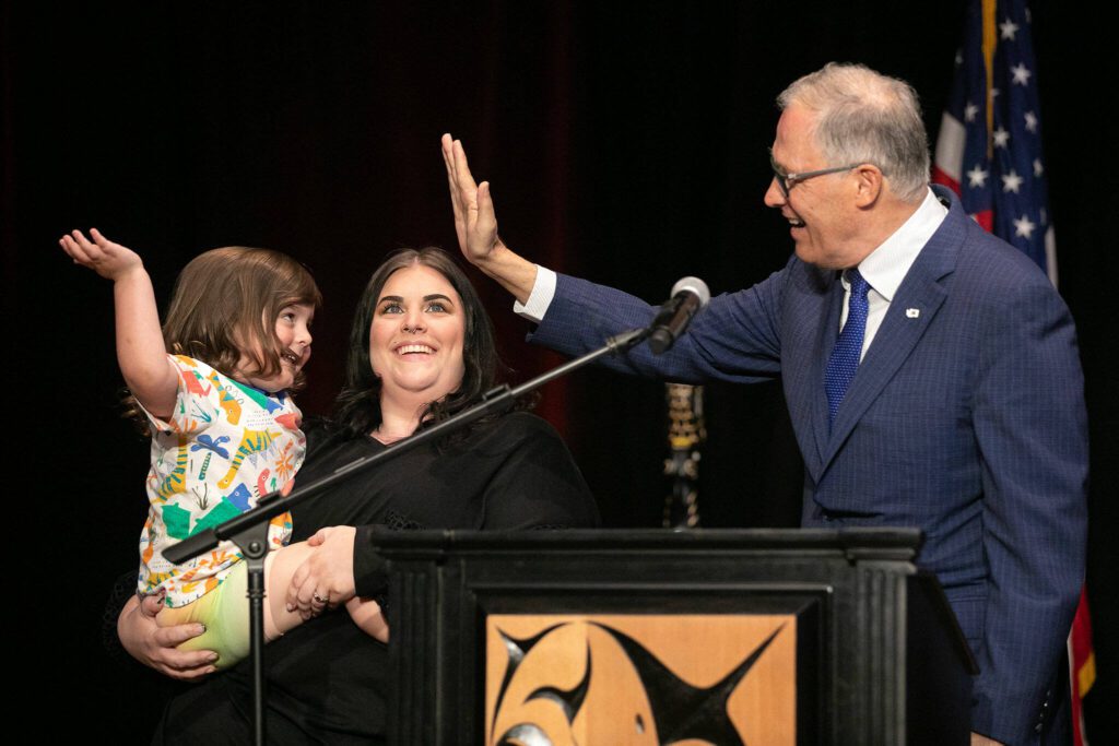 Gov. Jay Inslee receives a high five from a great-grandson of the late John McCoy before signing HB1879 on Tuesday, March 19, 2024, at Tulalip Casino’s Orca Ballroom in Tulalip, Washington. (Ryan Berry / The Herald)
