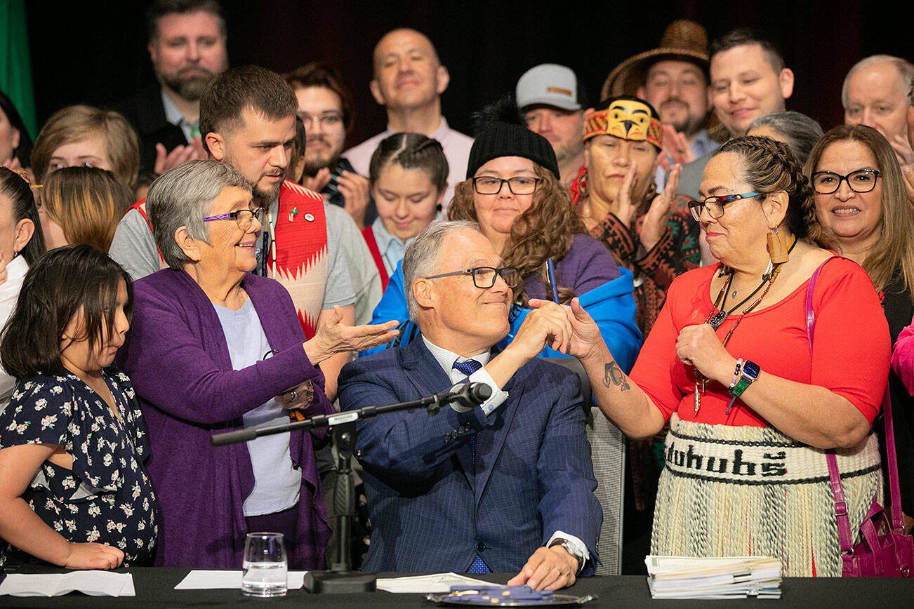Gov. Jay Inslee passes off a pen after signing HB1879 on Tuesday, March 19, 2024, at Tulalip Casino’s Orca Ballroom in Tulalip, Washington. (Ryan Berry / The Herald)