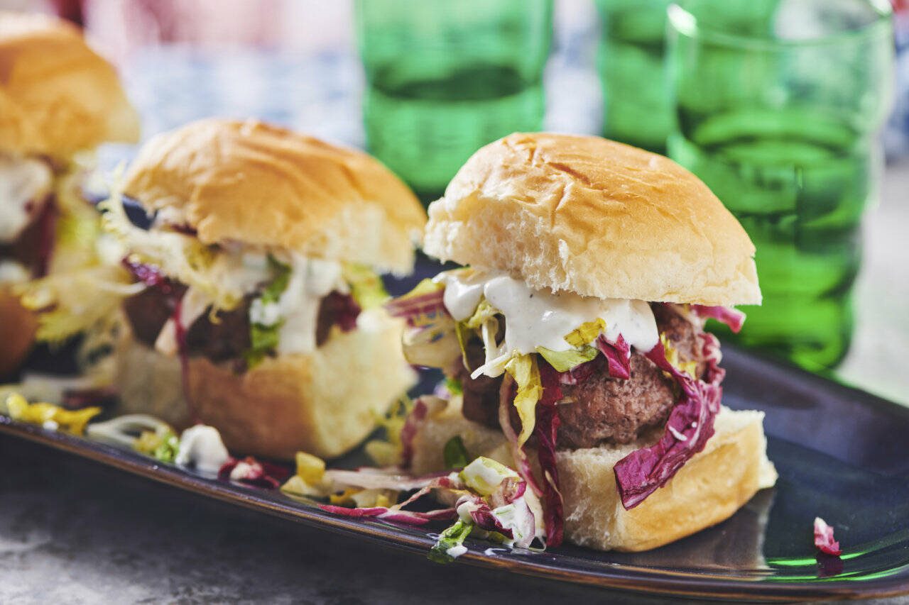 These chipotle sliders are garnished with a colorful lettuce slaw and blue cheese dressing. (Associated Press)
