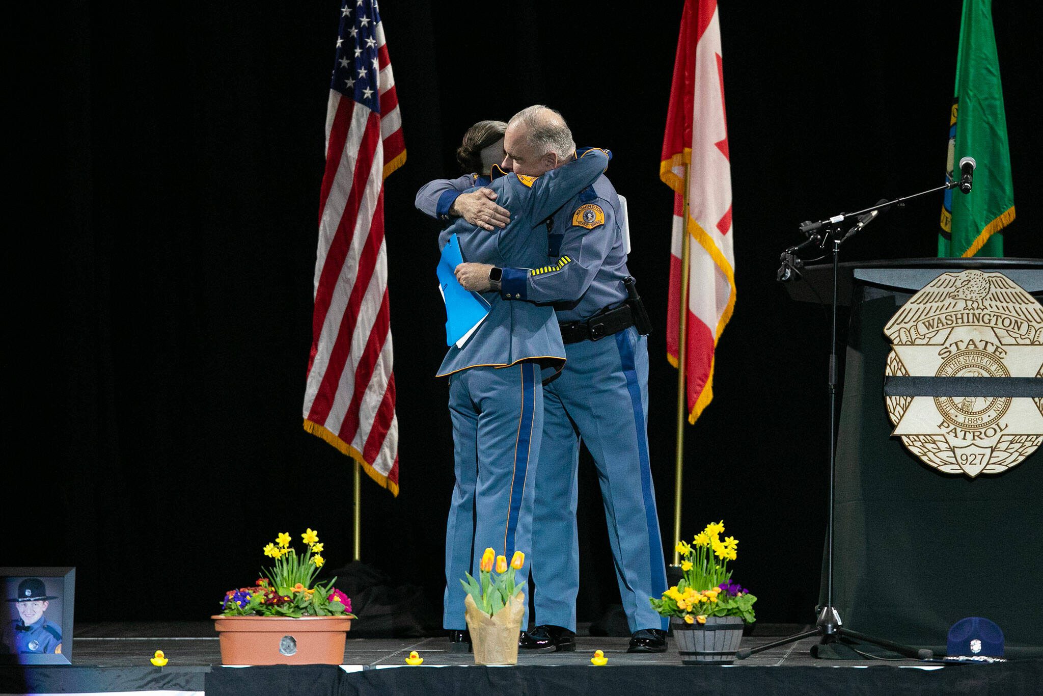 Captain Ron Mead and Corporal Alexis Robinson embrace during a memorial for Washington State Patrol trooper Chris Gadd on Tuesday, March 12, 2024, at Angel of the Winds Arena in Everett, Washington. (Ryan Berry / The Herald)