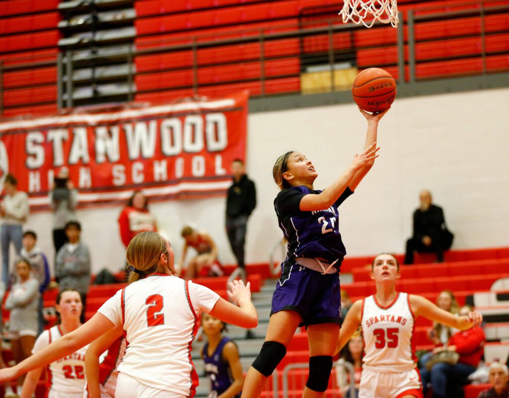 Kamiak’s Bella Hasan finishes at the rim with a driving layup against Stanwood on Nov. 30, 2023, at Stanwood High School in Stanwood. (Ryan Berry / The Herald)
