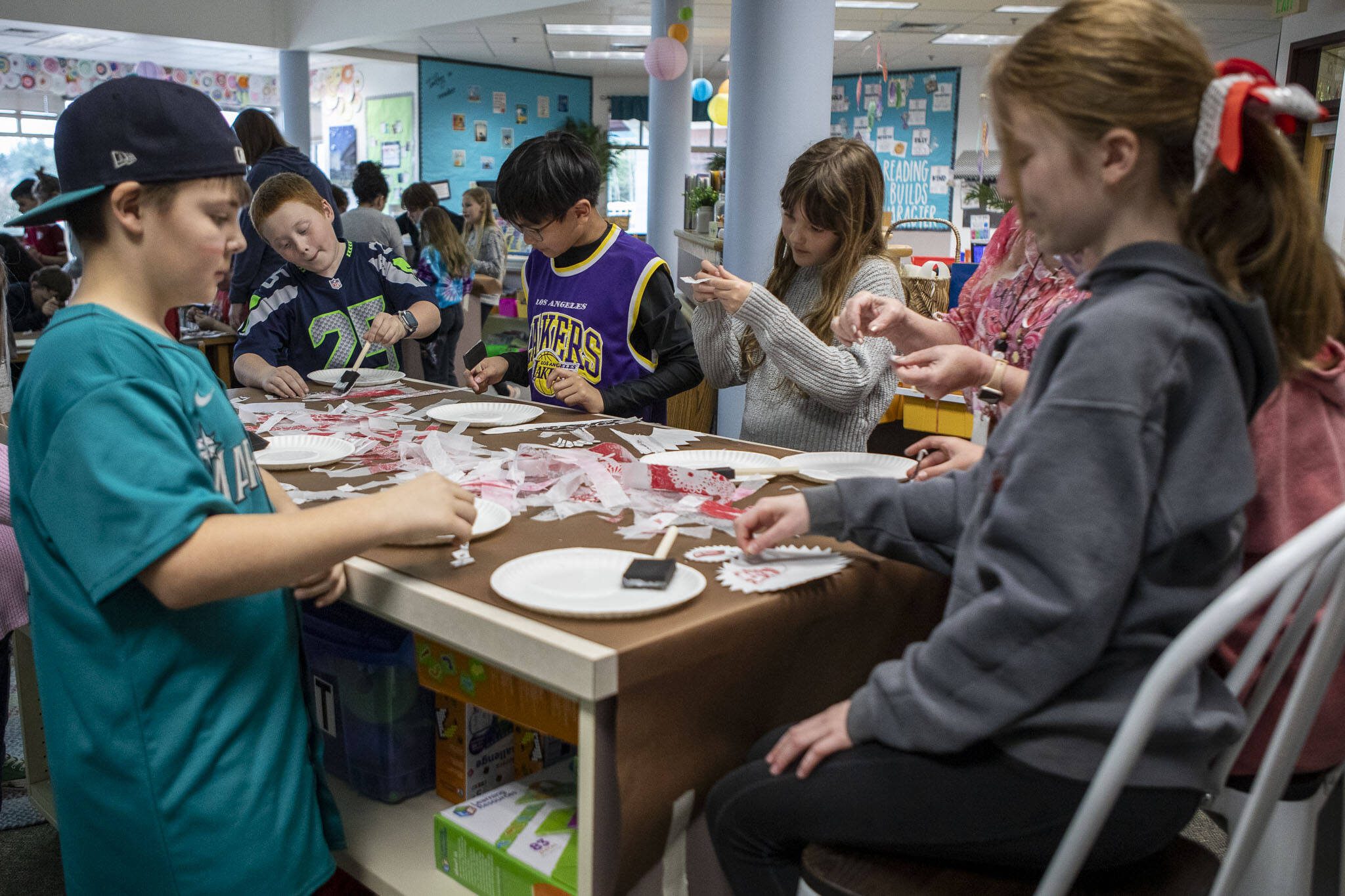 Students work on cutting pieces of paper for a mural during the "Afternoon of the Arts" program, where students spend part of the day on an art project at Utsalady Elementary on March 22, 2024 in Camano, Washington. (Annie Barker / The Herald)
