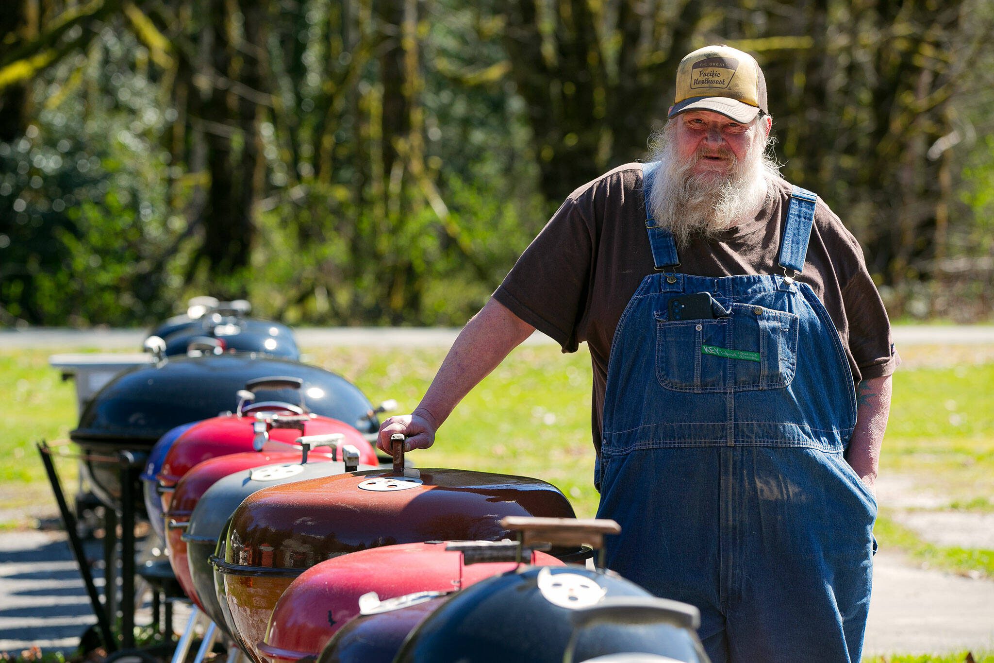 Jimmer De Groot strikes a pose à la George Stephen — the inventor of the Weber kettle — with his 26-inch Copper Mist Chief grill on March 31 near the Grotto sign on U.S. 2 between Baring and Skykomish. (Ryan Berry / The Herald)