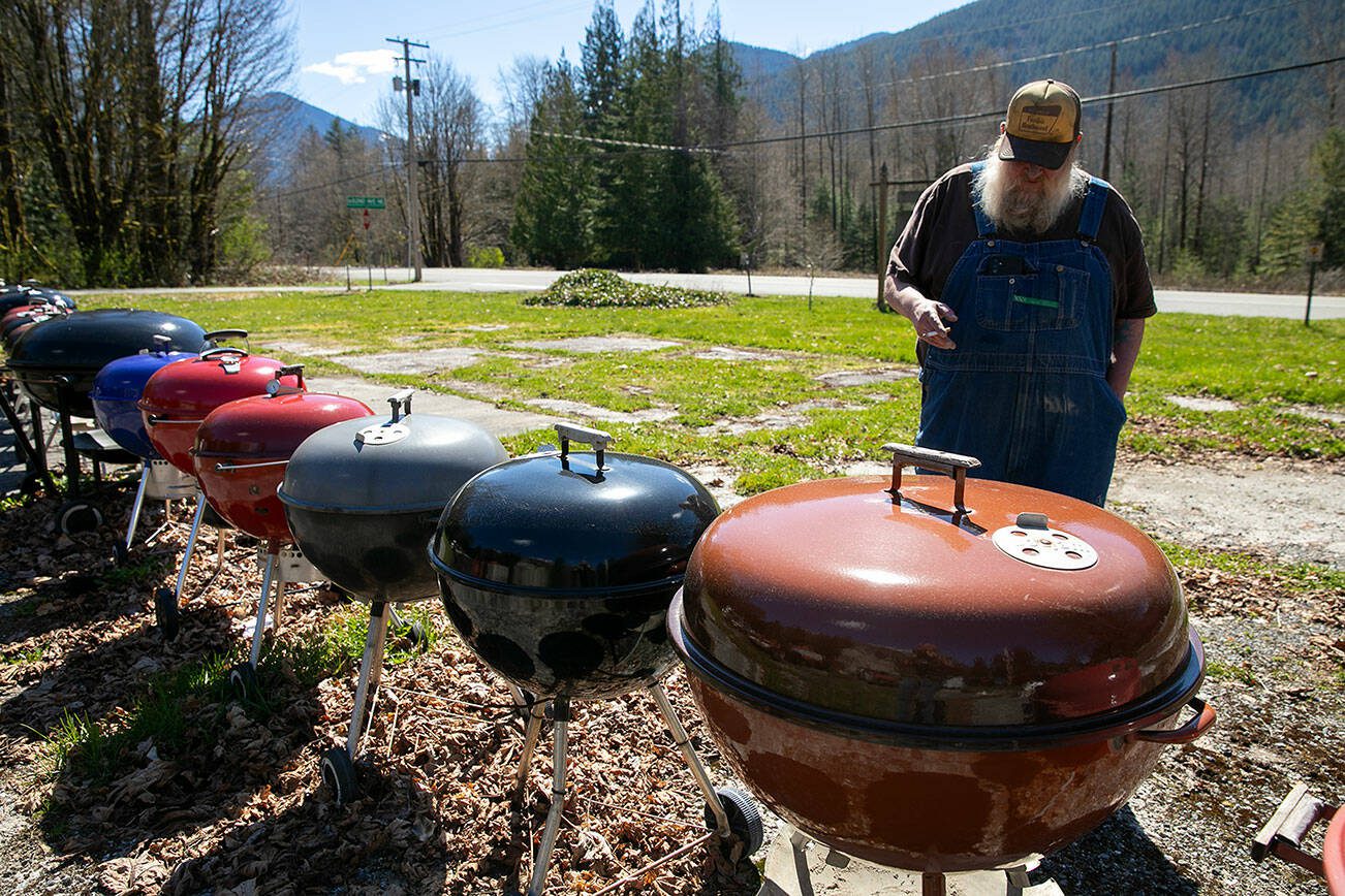 Jimmer DeGroot stands along the line of weber grills in his front yard on Sunday, March 31, 2024, in Grotto, Washington. (Ryan Berry / The Herald)