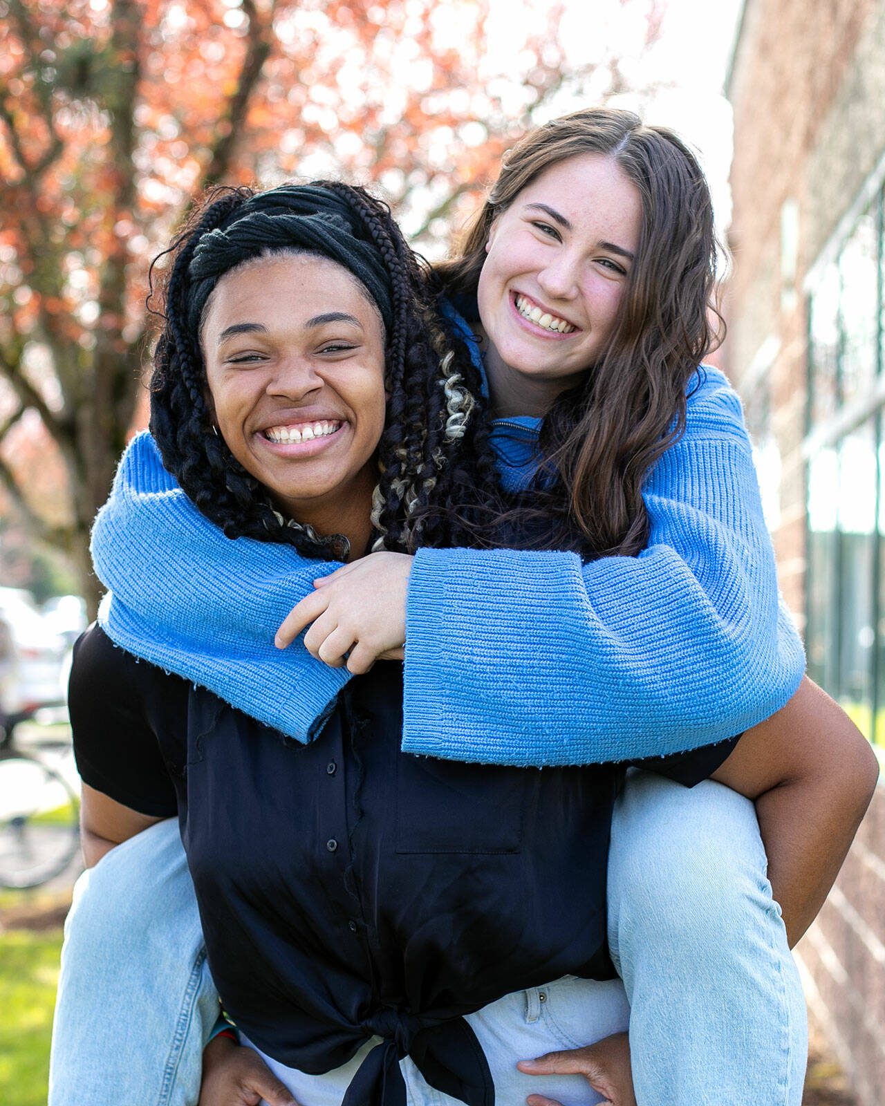 Gianna Frank gives a piggy-back ride to best friend Claire Michal on Monday, April 1, 2024, outside the YMCA in Marysville, Washington. The Marysville School District seniors have each attended the U.S. Senate Youth Program — Michal last year and Frank this year — becoming the first tandem in program history to represent the same school district in consecutive years. (Ryan Berry / The Herald)