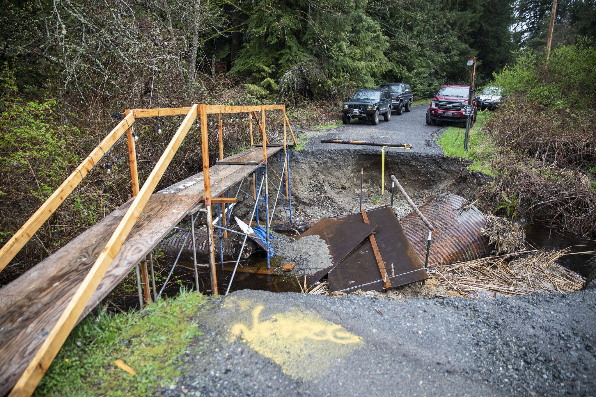 A makeshift bridge streches across the washed out culvert along 12th Avenue NW on Wednesday, April 3, 2024, near Marysville, Washington. (Olivia Vanni / The Herald)