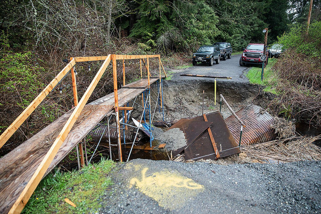 A makeshift bridge streches across the washed out culvert along 12th Avenue NW on Wednesday, April 3, 2024 in Marysville, Washington. (Olivia Vanni / The Herald)