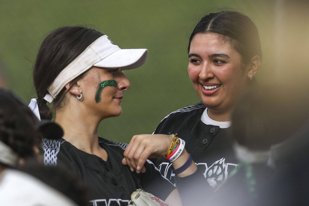 Jackson’s Allie Thomsen (22), left, and Yanina Sherwood (13), right, smile during a prep softball game between Stanwood and Jackson at Henry M. Jackson High School on Tuesday, April 2, 2024 in Mill Creek, Washington. Jackson won, 6-0. (Annie Barker / The Herald)
