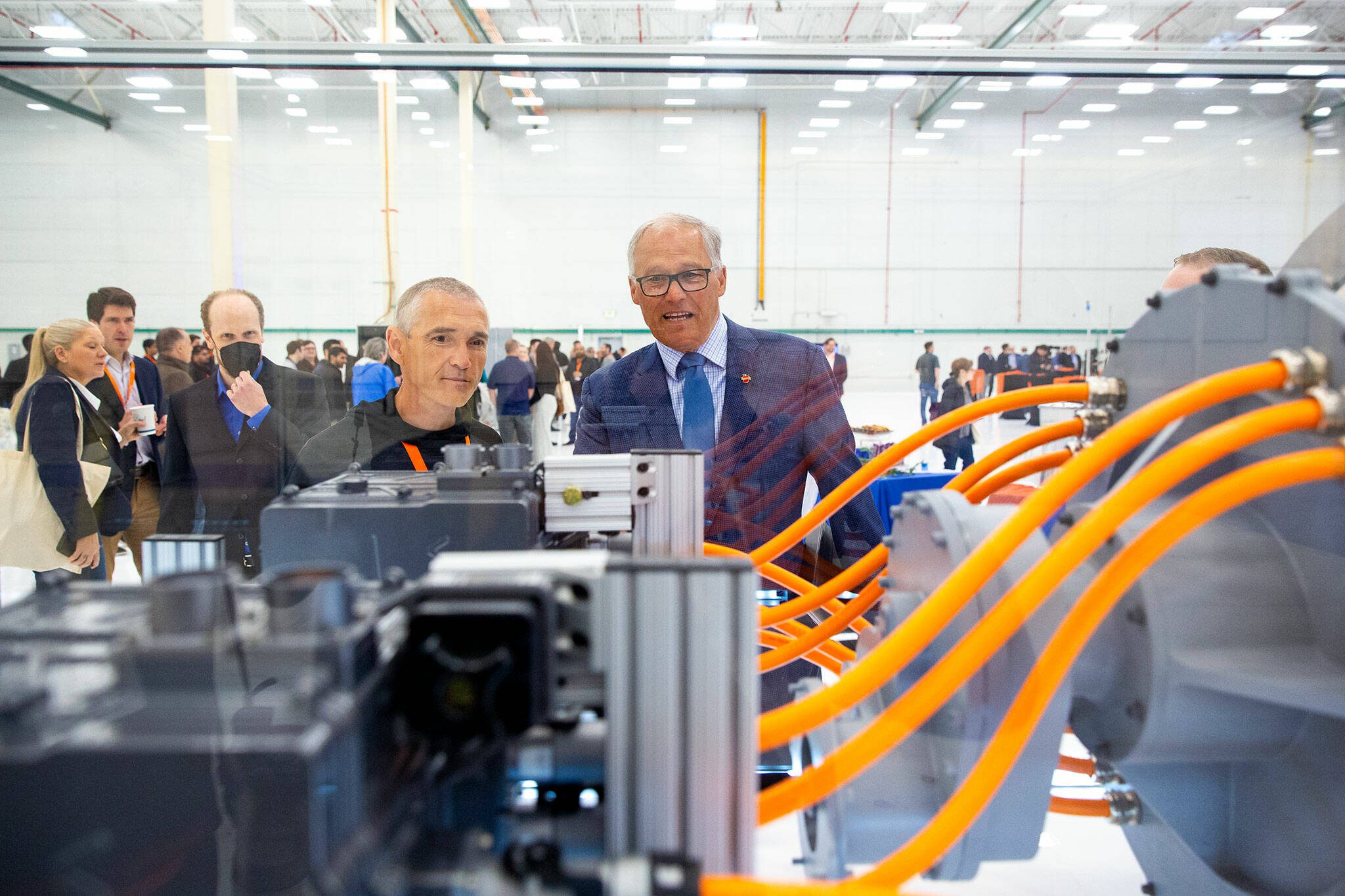 ZeroAvia founder and CEO Val Miftakhov, left, shows Gov. Jay Inslee a hydrogen-powered motor during an event at ZeroAvia’s new Everett facility on Wednesday, April 24, 2024, near Paine Field in Everett, Washington. (Ryan Berry / The Herald)