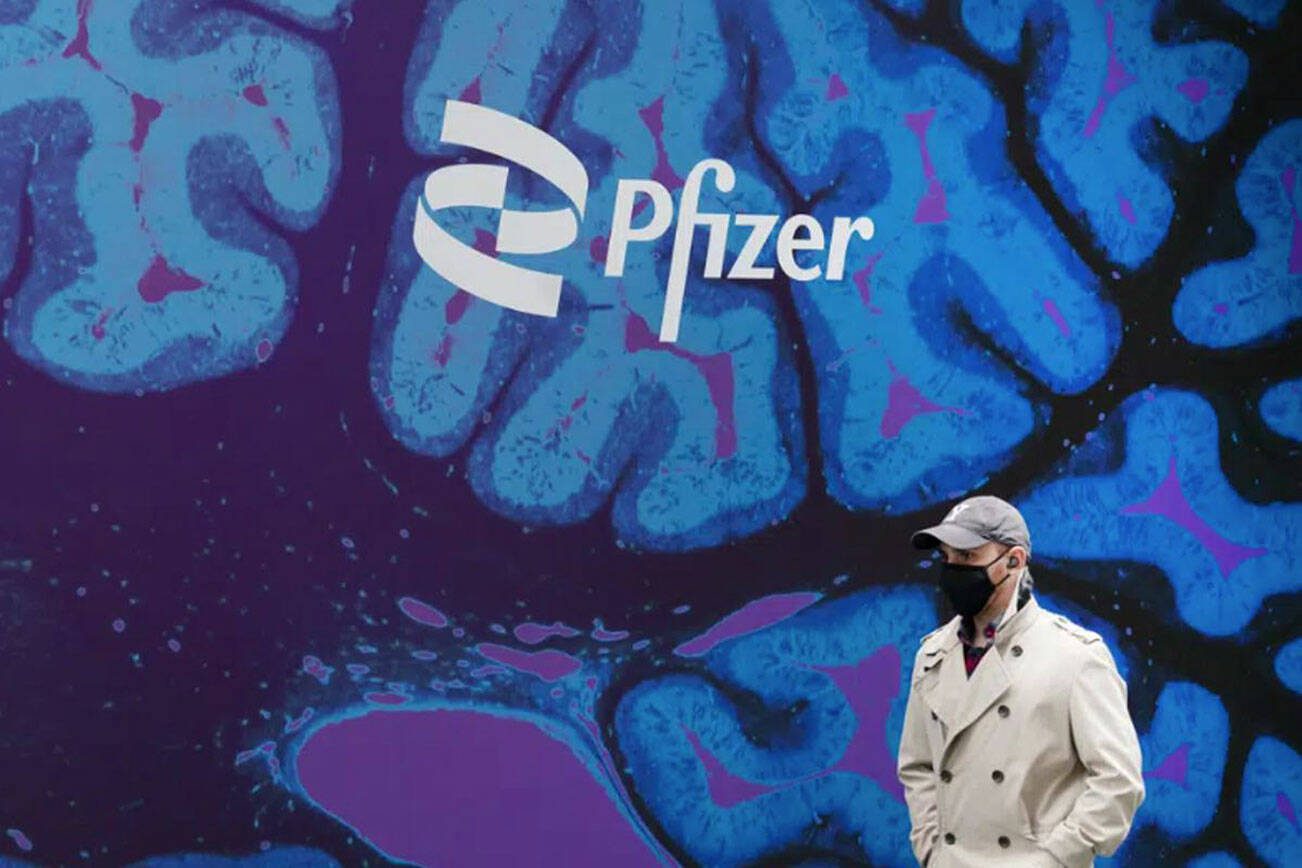 A man walks by Pfizer headquarters, Friday, Feb. 5, 2021, in New York. Pfizer will spend about $43 billion to buy Seagen and broaden its reach into cancer treatments, the pharmaceutical giant said Monday, March 13, 2023. (AP Photo / Mark Lennihan, File)