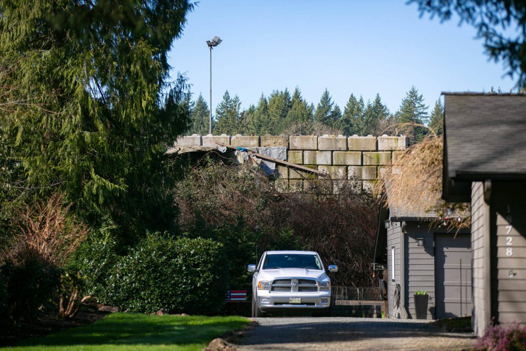 A cement block wall holds back refuse at DTG Enterprises behind a home on Tuesday, March 5, 2024, in Snohomish, Washington. Years ago, the homes on 109th Ave SE overlooked a 150-foot drop into an old gravel pit. (Ryan Berry / The Herald)
