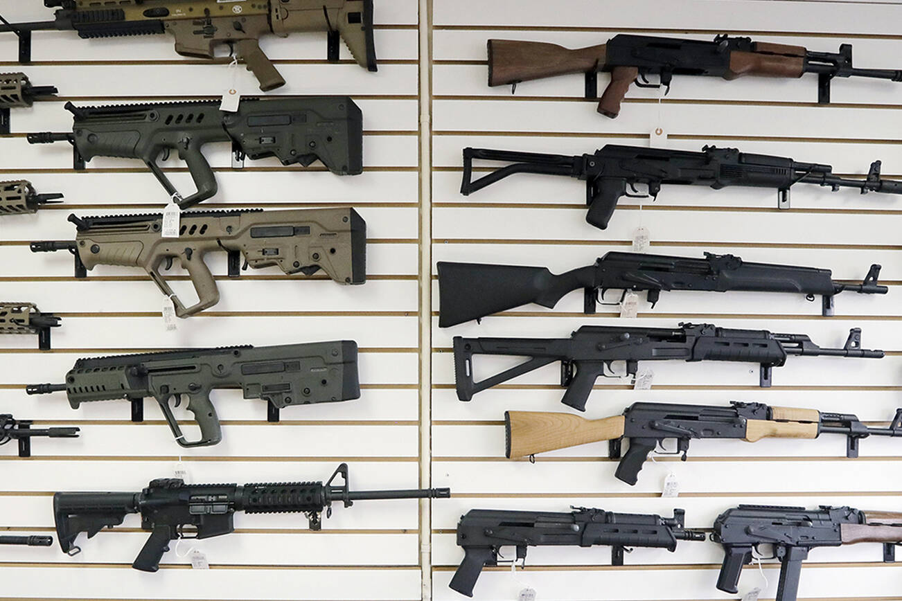 FILE - In this photo taken Oct. 2, 2018, semi-automatic rifles fill a wall at a gun shop in Lynnwood, Wash. Gov. Jay Inslee is joining state Attorney General Bob Ferguson to propose limits to magazine capacity and a ban on the sale of assault weapons. (AP Photo/Elaine Thompson, File)