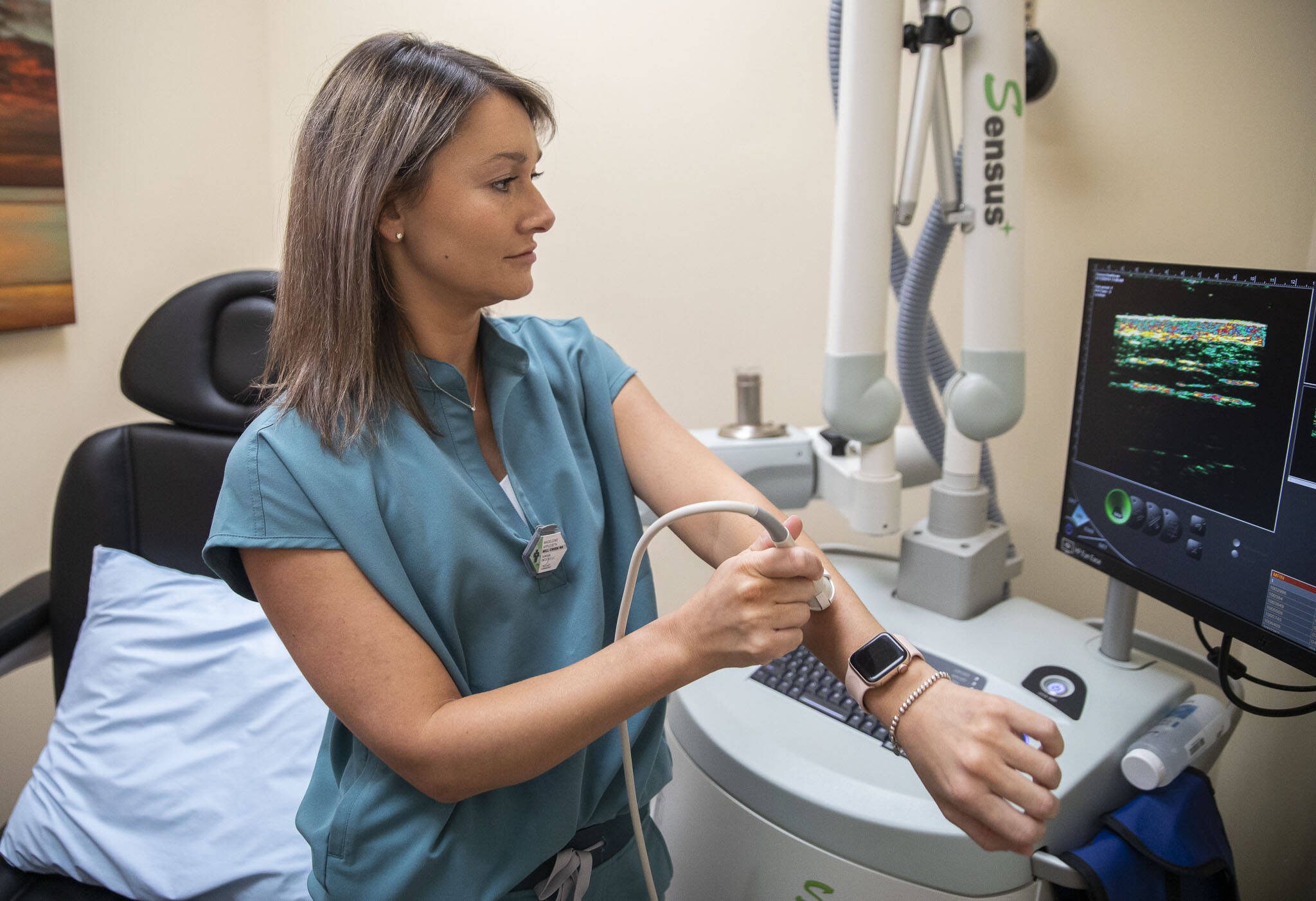 Radiation Therapist Madey Appleseth demonstrates how to use ultrasound technology to evaluate the depth of a mole on her arm on Wednesday, April 17, 2024 in Mill Creek, Washington. This technology is also used to evaluate on potential skin cancer on patients. (Olivia Vanni / The Herald)