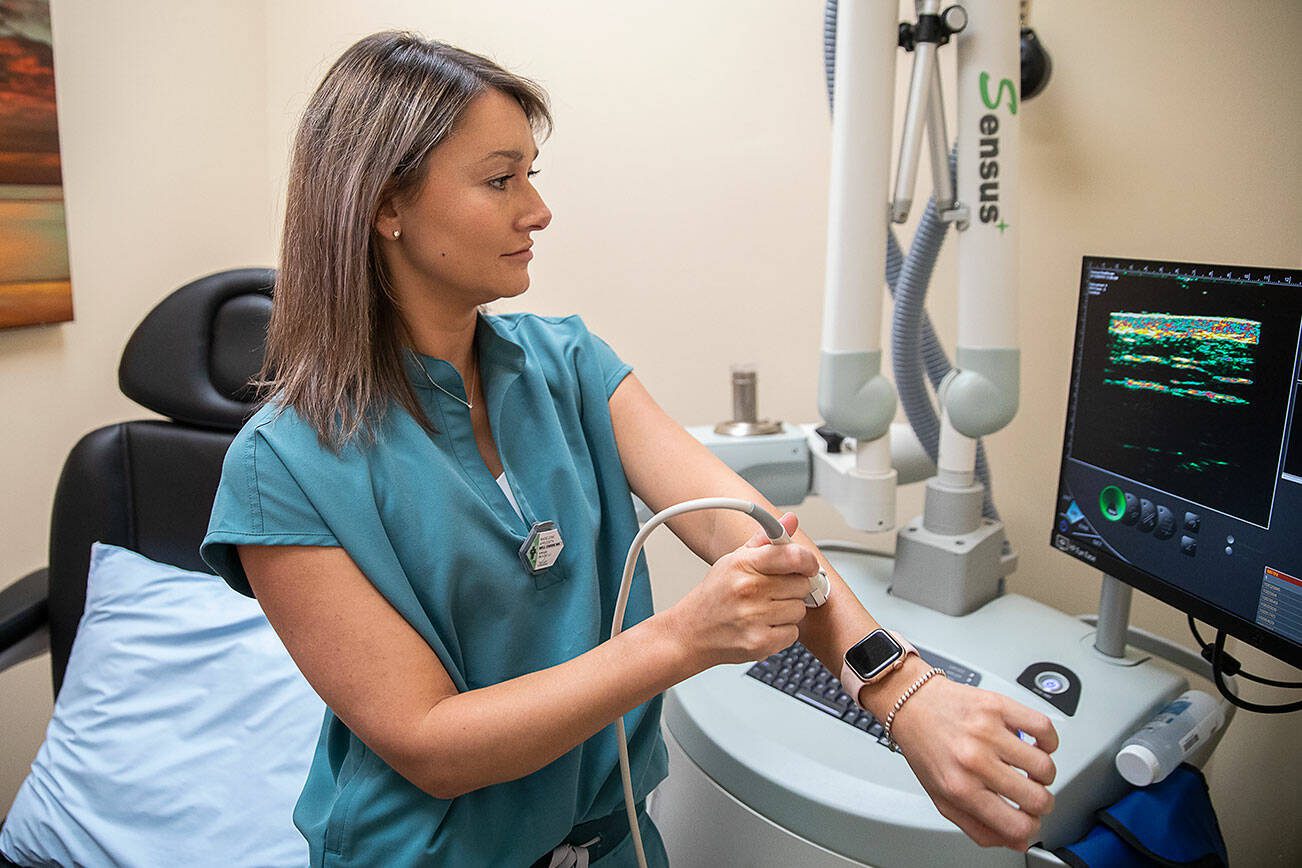 Radiation Therapist Madey Appleseth demonstrates how to use ultrasound technology to evaluate the depth of a mole on her arm on Wednesday, April 17, 2024 in Mill Creek, Washington. This technology is also used to evaluate on potential skin cancer on patients. (Olivia Vanni / The Herald)