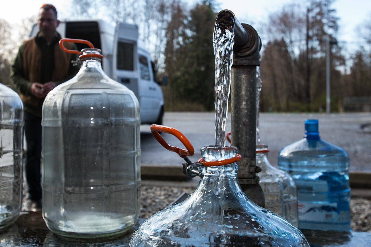 People fill up various water jug and containers at the artesian well on 164th Street on Monday, April 2, 2018 in Lynnwood, Wa. (Andy Bronson / The Herald)