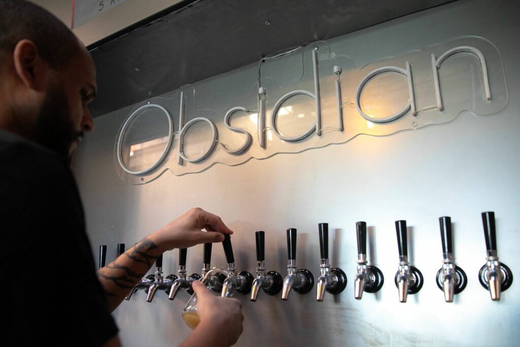 Craig Chambers pours a beer from the tap at Obsidian Beer Hall on Friday, April 12, 2024, in downtown Everett, Washington. (Ryan Berry / The Herald) 
