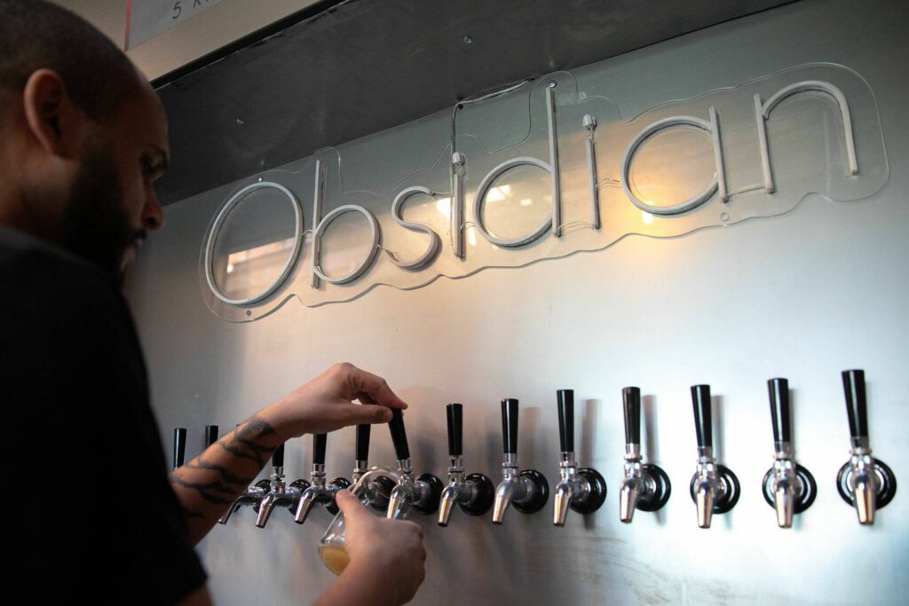 Craig Chambers pours a beer from the tap at Obsidian Beer Hall on Friday, April 12, 2024, in downtown Everett, Washington. (Ryan Berry / The Herald) 
