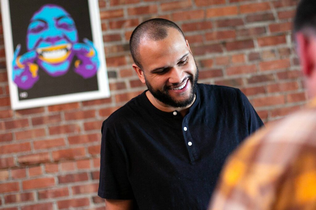 Craig Chambers cracks a smile while speaking with a guest at Obsidian Beer Hall on Friday, April 12, 2024, in downtown Everett, Washington. Art by Jessie Lipscomb or Momma Lips Draws hangs behind him. (Ryan Berry / The Herald)
Craig Chambers cracks a smile while speaking with a guest at Obsidian Beer Hall on Friday, April 12, 2024, in downtown Everett, Washington. (Ryan Berry / The Herald) 
