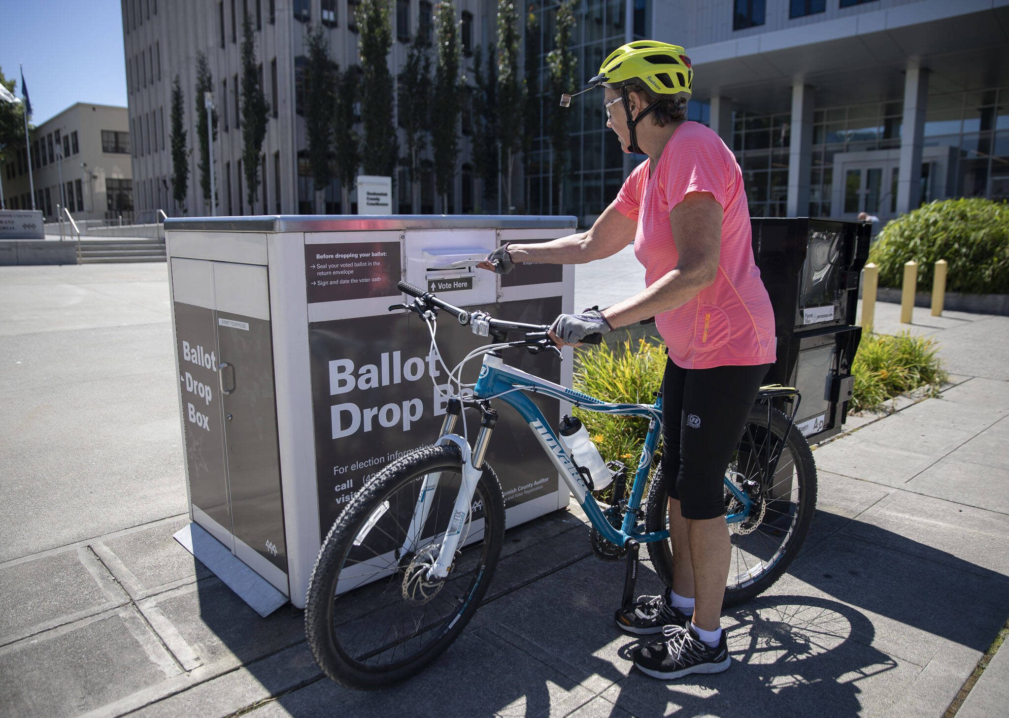 Dorothy Crossman rides up on her bike to turn in her ballot on Tuesday, Aug. 1, 2023 in Everett, Washington. (Olivia Vanni / The Herald)