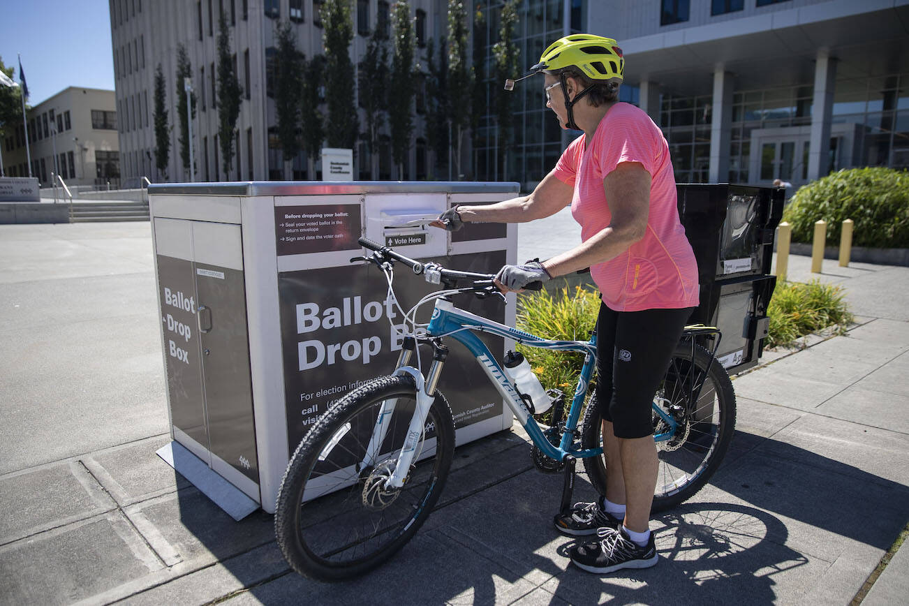 Dorothy Crossman rides up on her bike to turn in her ballot  on Tuesday, Aug. 1, 2023 in Everett, Washington. (Olivia Vanni / The Herald)