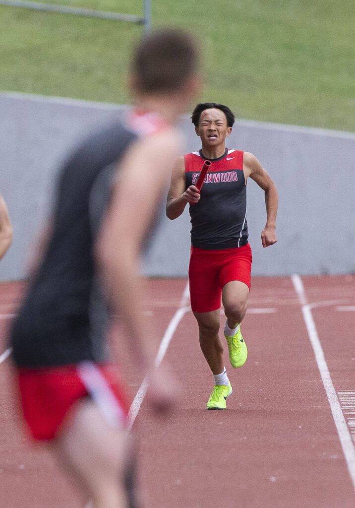 Stanwood’s leadoff runner in the boys 1,600-meter relay grimaces while running toward his teammate during the Eason Invitational at Snohomish High School on Saturday, April 20, 2024 in Snohomish, Washington. (Olivia Vanni / The Herald)
