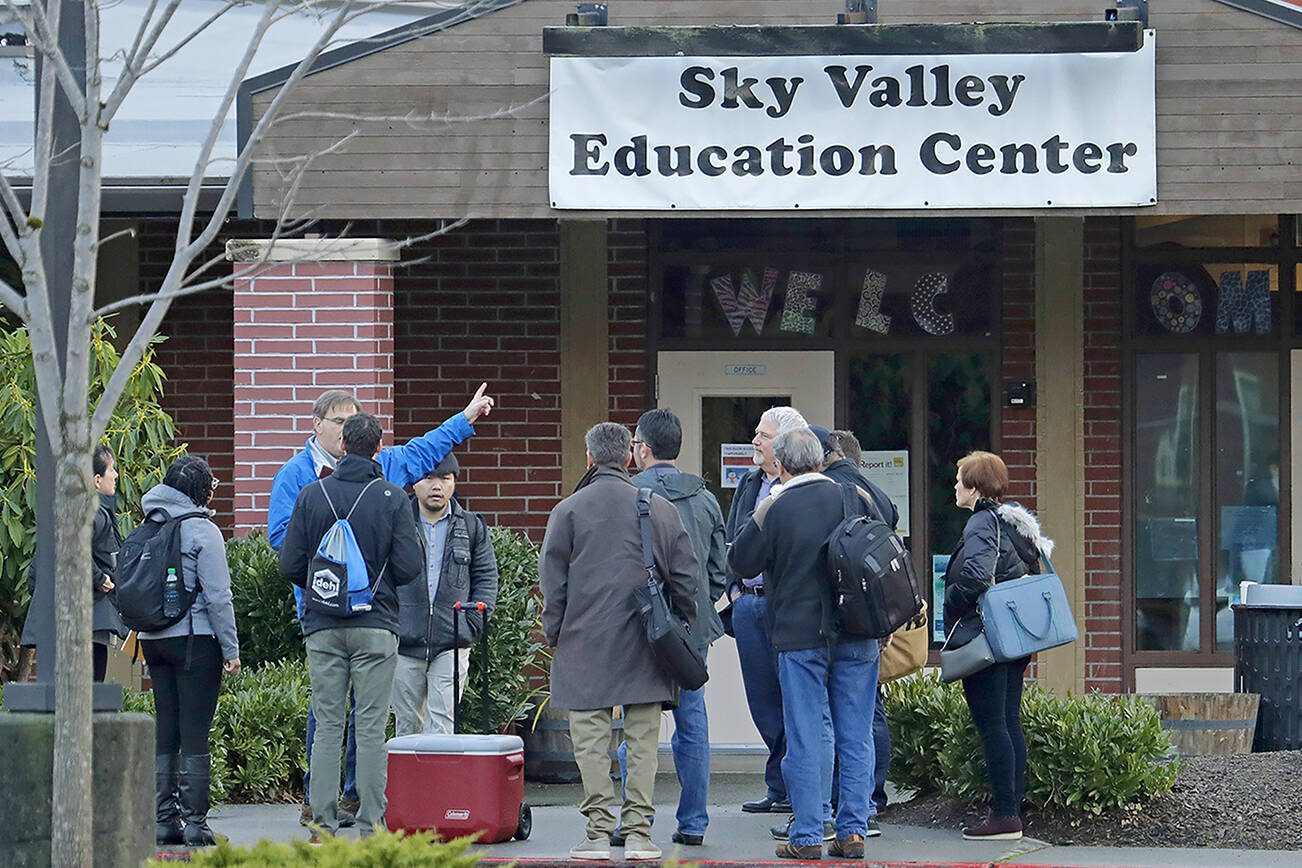 In this Jan. 4, 2019 photo, workers and other officials gather outside the Sky Valley Education Center school in Monroe, Wash., before going inside to collect samples for testing. The samples were tested for PCBs, or polychlorinated biphenyls, as well as dioxins and furans. A lawsuit filed on behalf of several families and teachers claims that officials failed to adequately respond to PCBs, or polychlorinated biphenyls, in the school. (AP Photo/Ted S. Warren)
