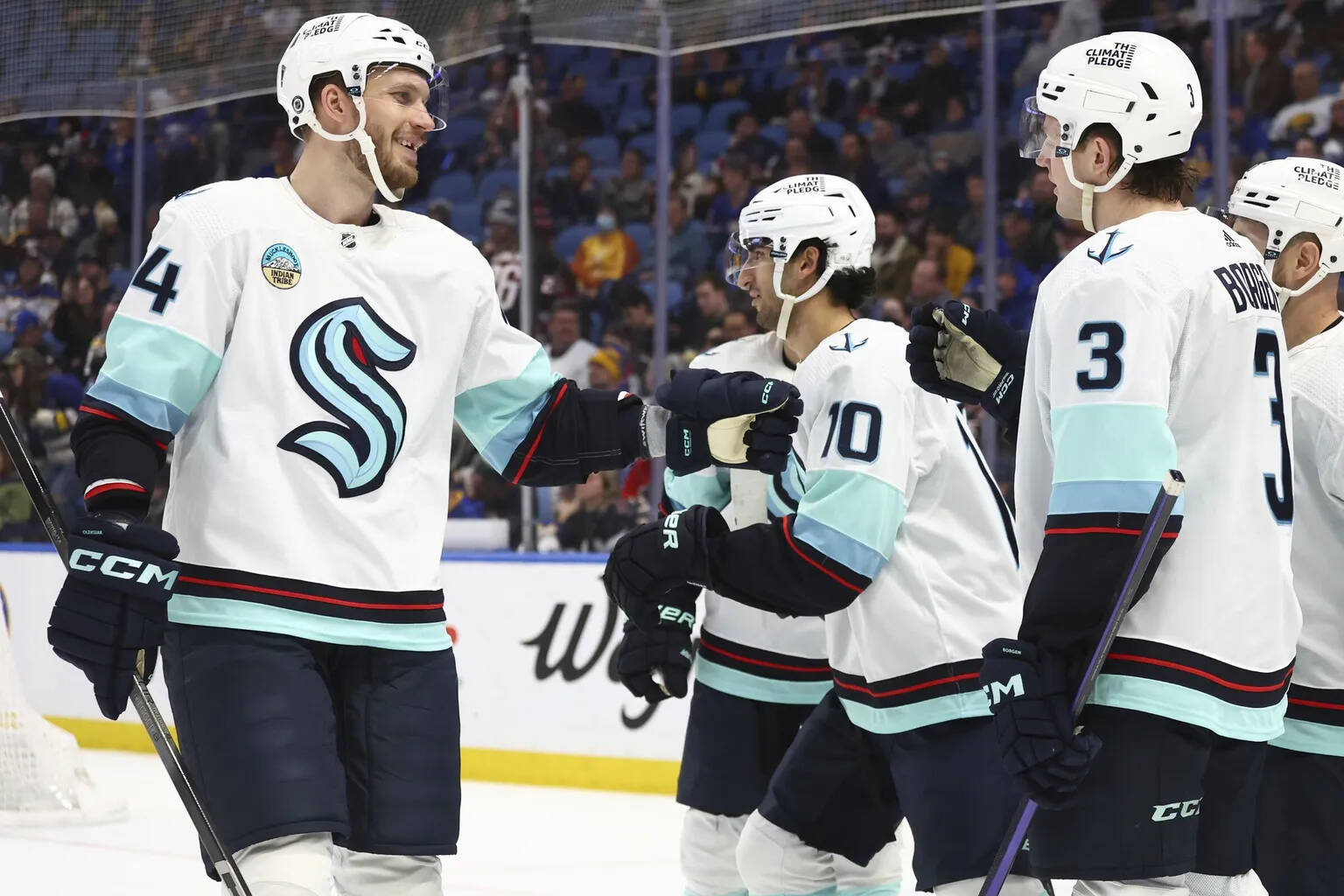 Seattle Kraken defensemen Jamie Oleksiak (24) and Will Borgen (3) celebrate a goal by center Matty Beniers (10) against the Buffalo Sabres during the second period of an NHL hockey game, Tuesday, in Buffalo, N.Y. (Jeffrey T. Barnes / The Associated Press)