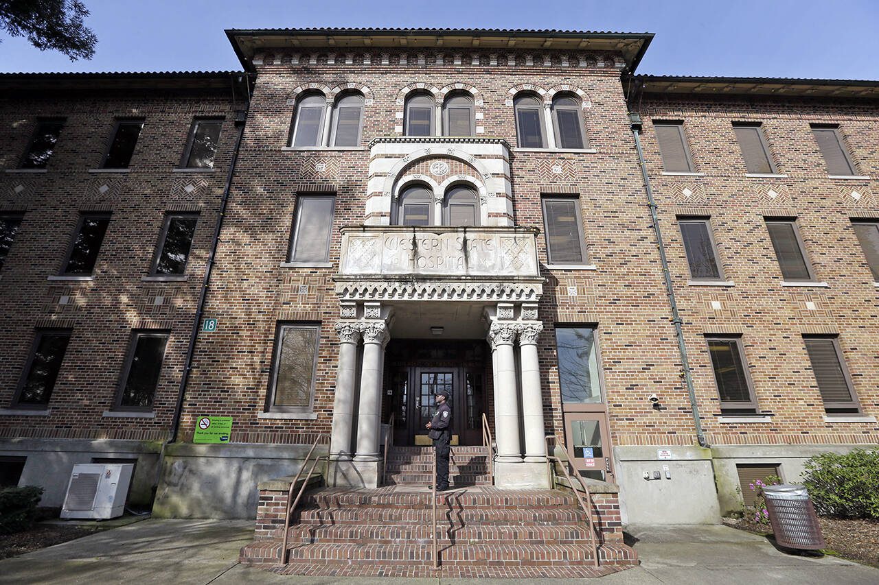 FILE - In this file photo taken April 11, 2017, a security officer stands on steps at the entrance to Western State Hospital, in Lakewood, Wash. When the Centers for Medicare and Medicaid Services conducted a surprise inspection at Western State Hospital in May 2018, they found so many glaring health and safety violations that they stripped the facility of its certification and cut its federal funding. (AP Photo/Elaine Thompson, File)