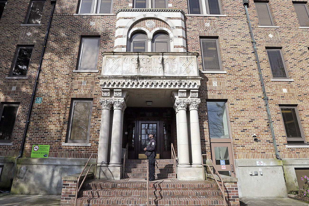FILE - In this file photo taken April 11, 2017, a security officer stands on steps at the entrance to Western State Hospital, in Lakewood, Wash. When the Centers for Medicare and Medicaid Services conducted a surprise inspection at Western State Hospital in May 2018, they found so many glaring health and safety violations that they stripped the facility of its certification and cut its federal funding. (AP Photo/Elaine Thompson, File)