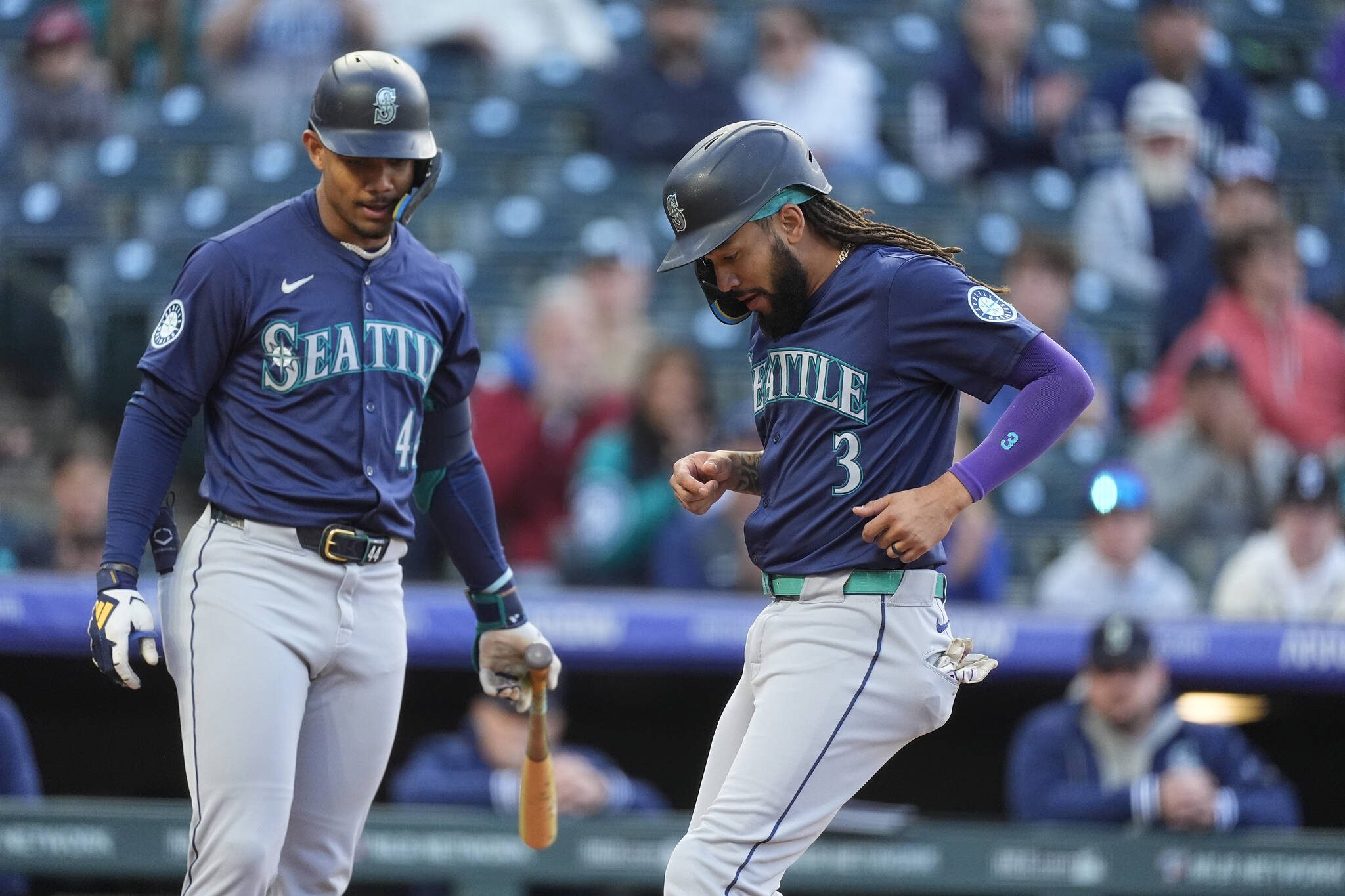 Seattle Mariners’ J.P. Crawford (3) scores on a wild pitch as Julio Rodríguez, left, looks on in the second inning of the second game of a baseball doubleheader against the Colorado Rockies Sunday, April 21, 2024, in Denver. (AP Photo/David Zalubowski)