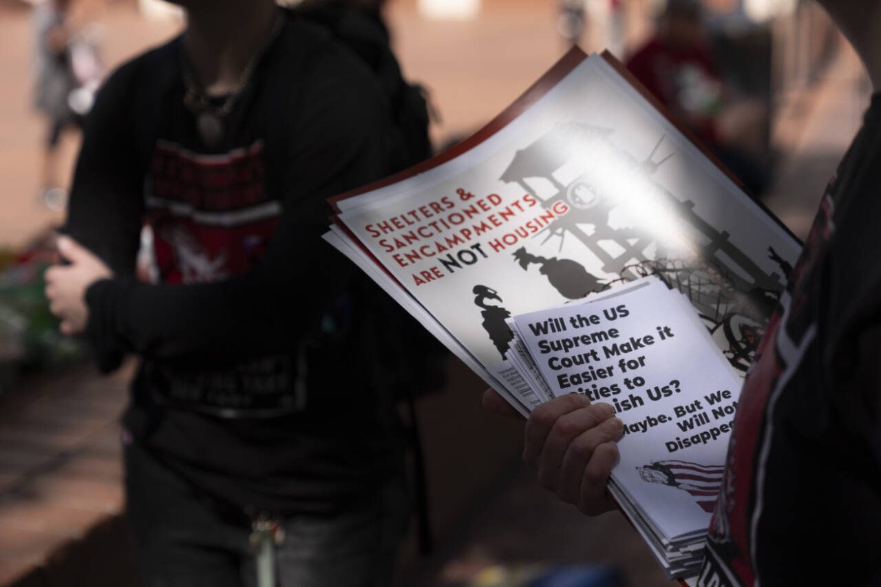 Volunteers with Stop the Sweeps hold flyers as they talk with people during a rally outside The Pioneer Courthouse on Monday, April 22, 2024, in Portland, Ore. The rally was held on Monday as the Supreme Court wrestled with major questions about the growing issue of homelessness. The court considered whether cities can punish people for sleeping outside when shelter space is lacking. (Jenny Kane / Associated Press)