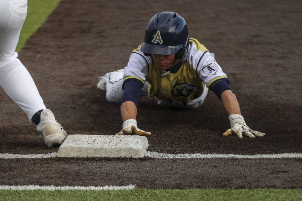 An Arlington player slides into first during a baseball game between Monroe and Arlington at Monroe High School on Friday, April 26, 2024 in Monroe, Washington. Monroe secured a win in an eighth inning, 4-3. (Annie Barker / The Herald)
