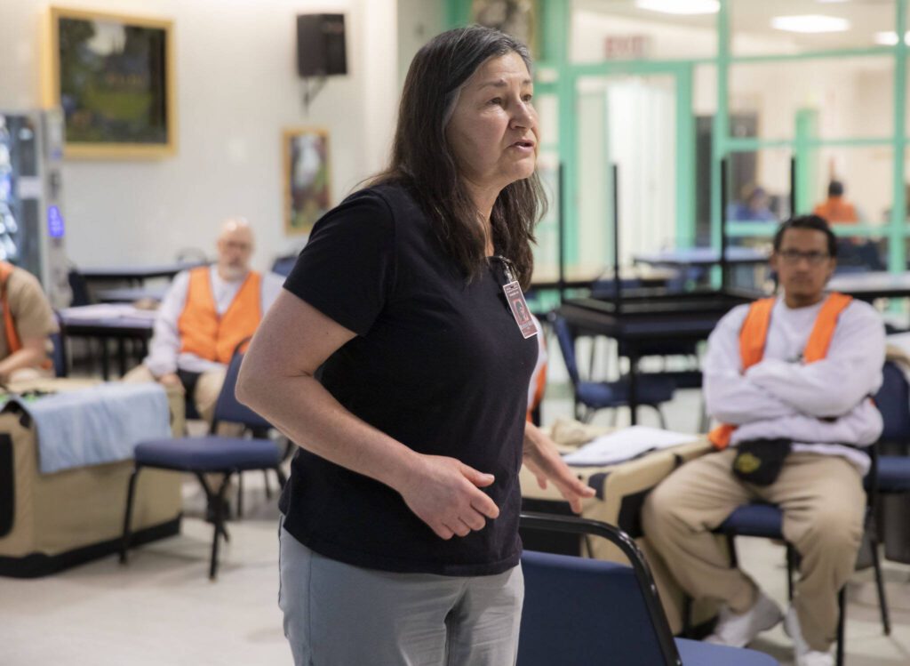 Sue Meinzinger, the founder and executive director Summit Assistance Dogs, talks prisoners through the first training exercise of the day during a weekly meeting of the Summit Assistance Dogs program at the Monroe Correctional Complex on Tuesday, Feb. 6, 2024 in Monroe, Washington. (Olivia Vanni / The Herald)
